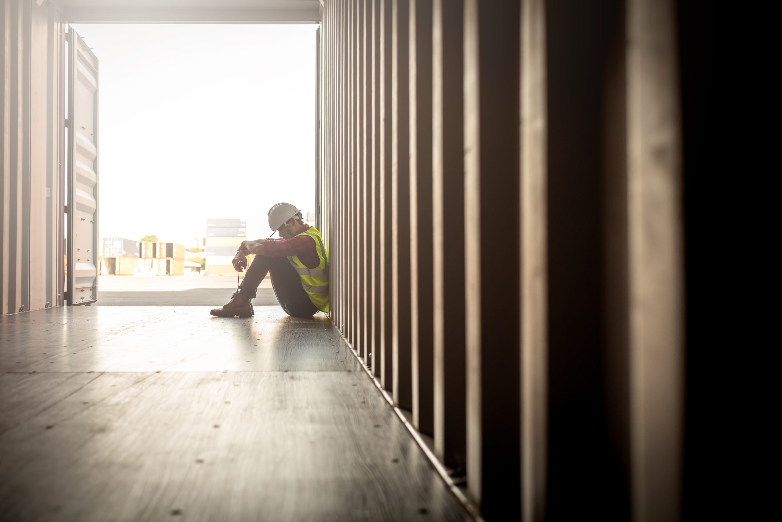 Stressed despair staff in logistic business sittng in container box at shipyard